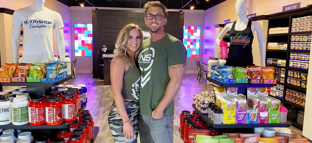 man and woman, new owners of Nutrishop Lexington, standing in front of their store